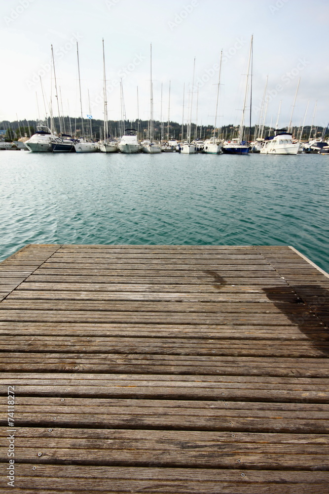 wood marina pontoon with sail boats and yacht