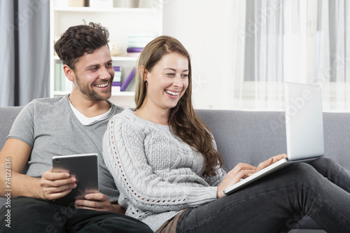 Junges glückliches Paar sitzt zu Hause auf dem Sofa 