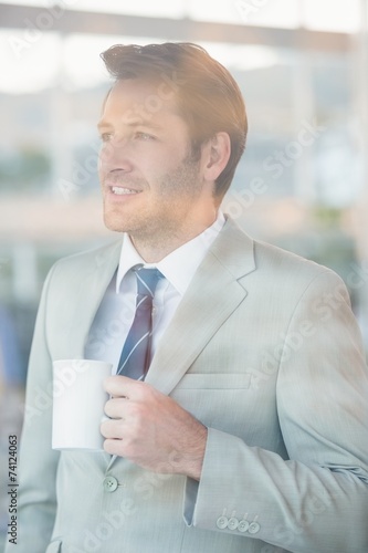 Handsome businessman holding cup of coffee