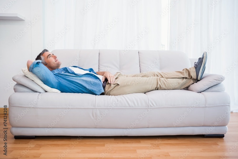 Smiling man lying and relaxing on the couch Smiling man lying and relaxing on the couch