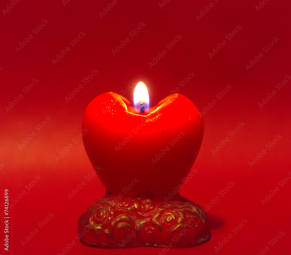 Red heart candle on red background