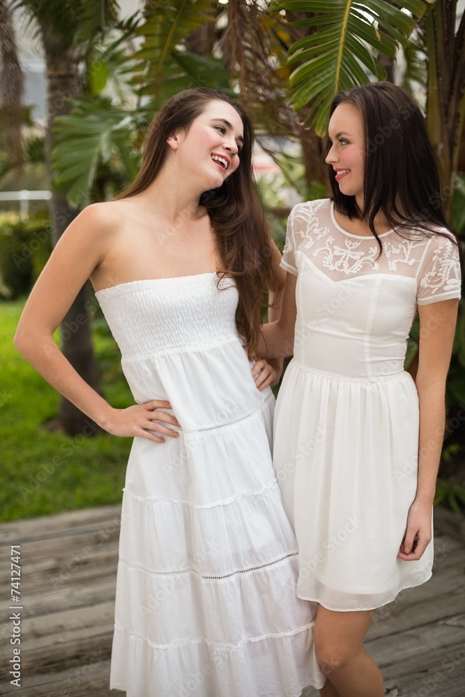 Pretty friends smiling in white dresses