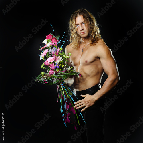  male fitness model shirtless holding a bouquet of flowers. 