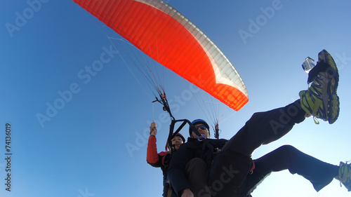 Tourist playing paragliding guided by a pilot