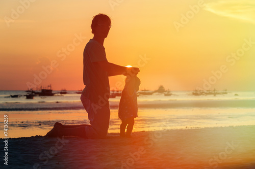 Silhouette of father and little daughter on sunset