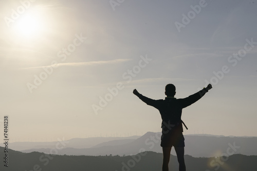 young tourist in the mountains with his arms raised