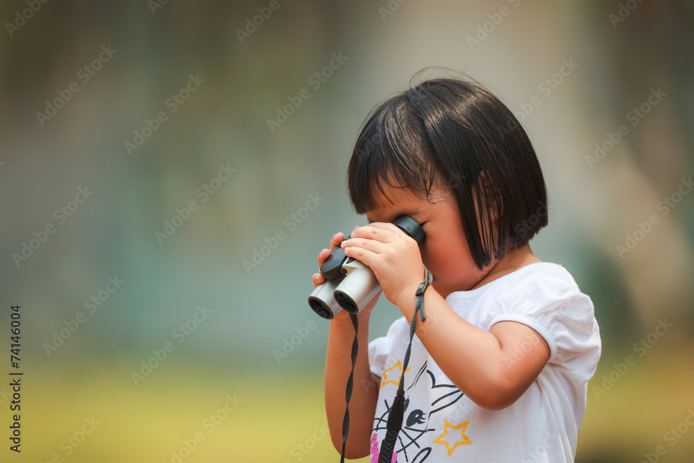 An Asian little girl using a binoculars by her own