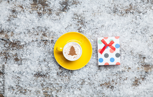Cappuccino with christmas tree shape and gift box on artificial