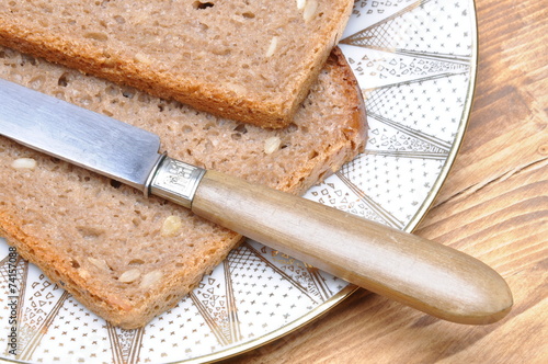 Sliced bread with knife on a plate and wooden table