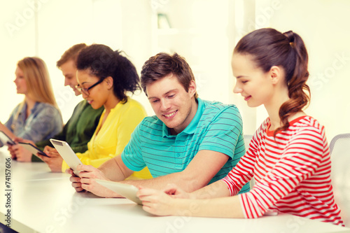 smiling students looking at tablet pc at school