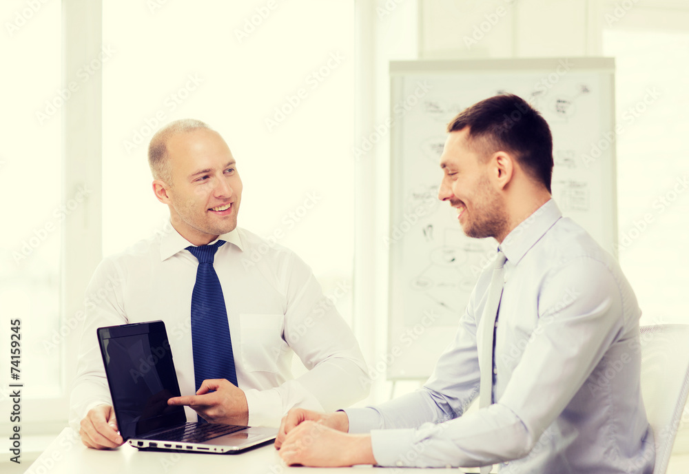 two smiling businessmen with laptop in office two smiling businessmen with laptop in office