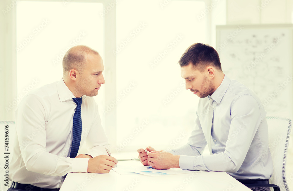 two serious businessman with papers in office two serious businessman with papers in office