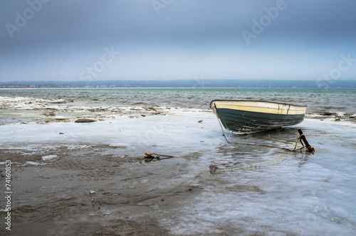 Fishing boat on the shore of the Baltic Sea. Winter landscape