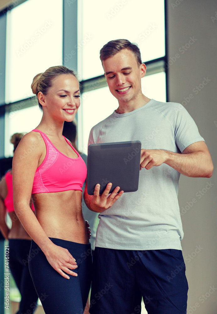 smiling young woman with personal trainer in gym smiling young woman with personal trainer in gym