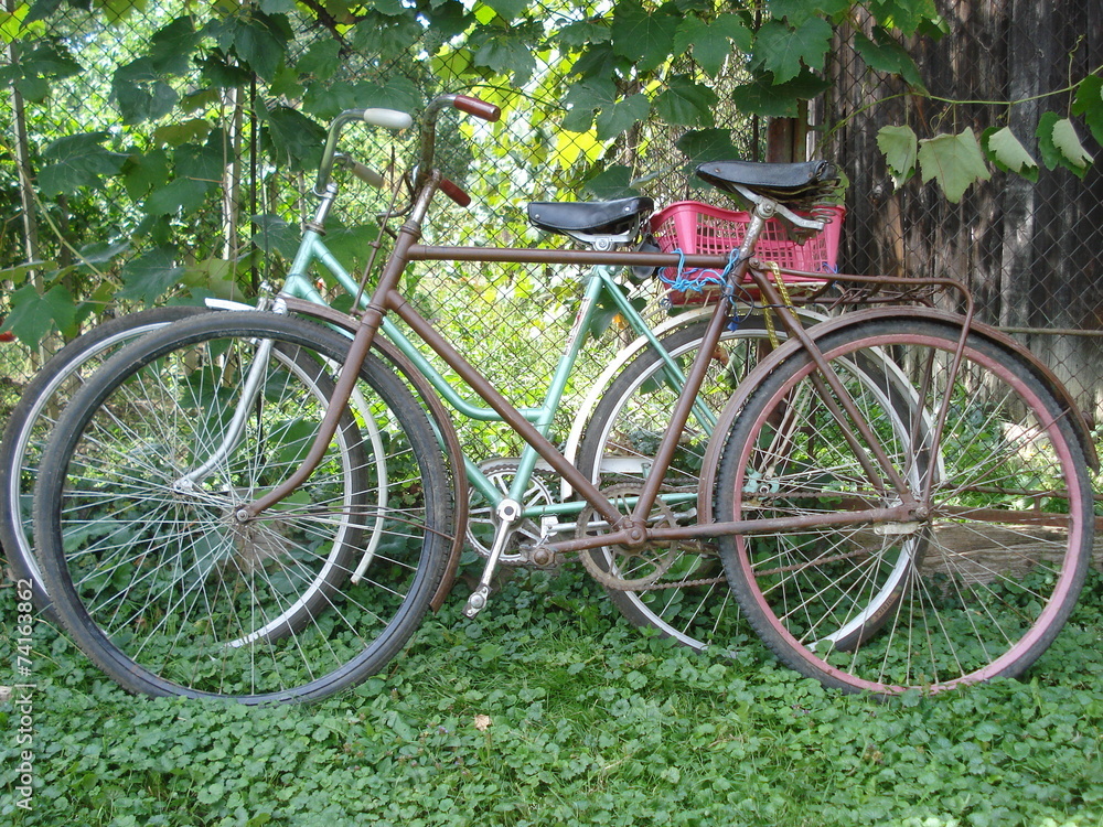 Old bicycles leaning against wire mesh fence in the countryside