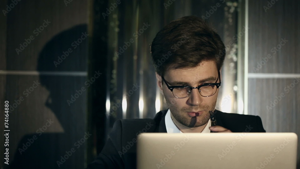 Young intelligent man smoking an electronic cigarette indoors. Young intelligent man smoking an electronic cigarette indoors.