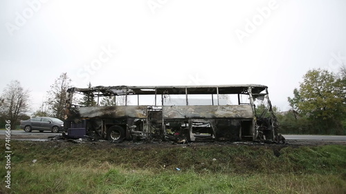 Burned-out passenger bus on the side of the road photo