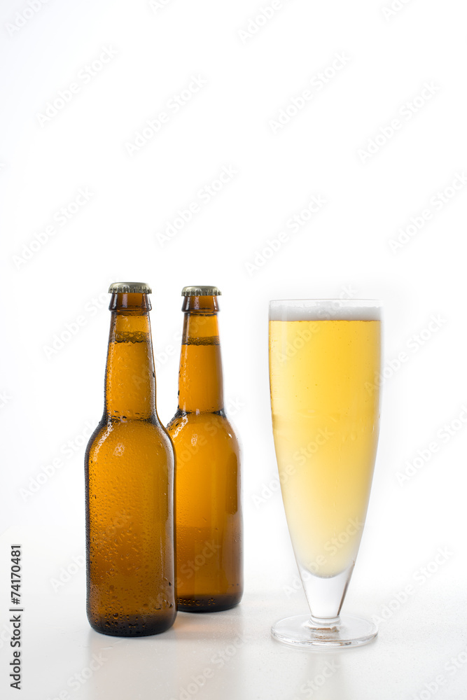 Two brown beer bottles and a full glass of beer. Two brown beer bottles and a full glass of beer.