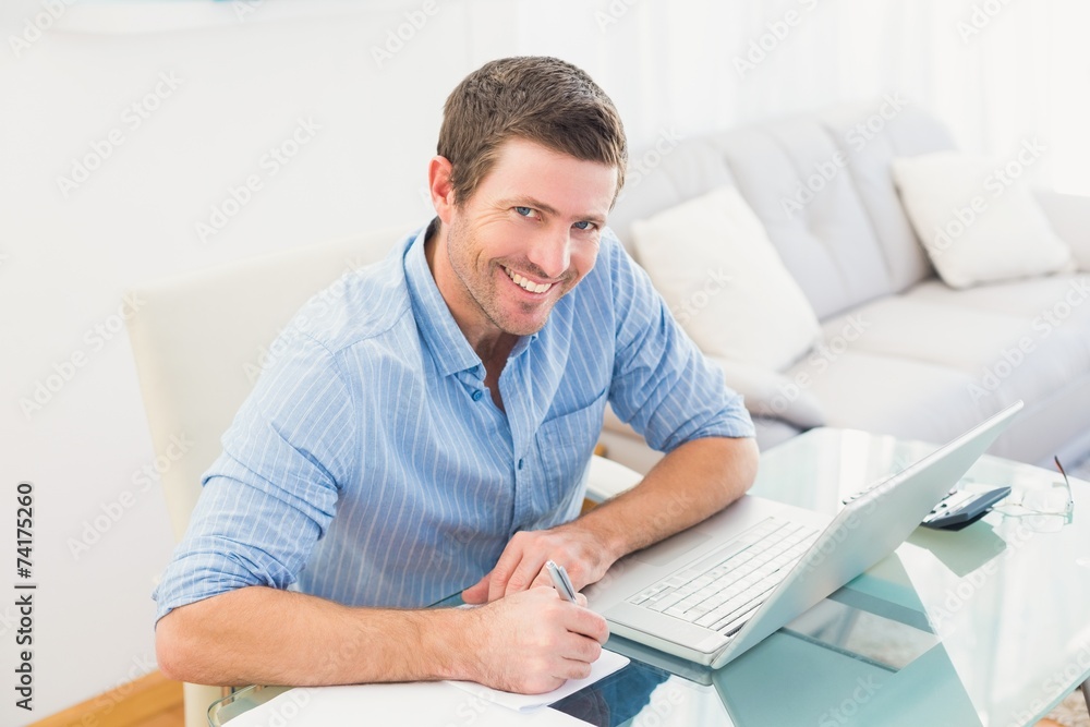 Smiling businessman writing at his desk Smiling businessman writing at his desk