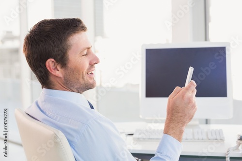 Smiling businessman sending a text