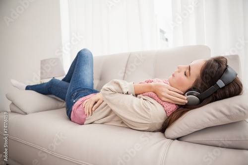 Pretty brunette listening to music on the couch