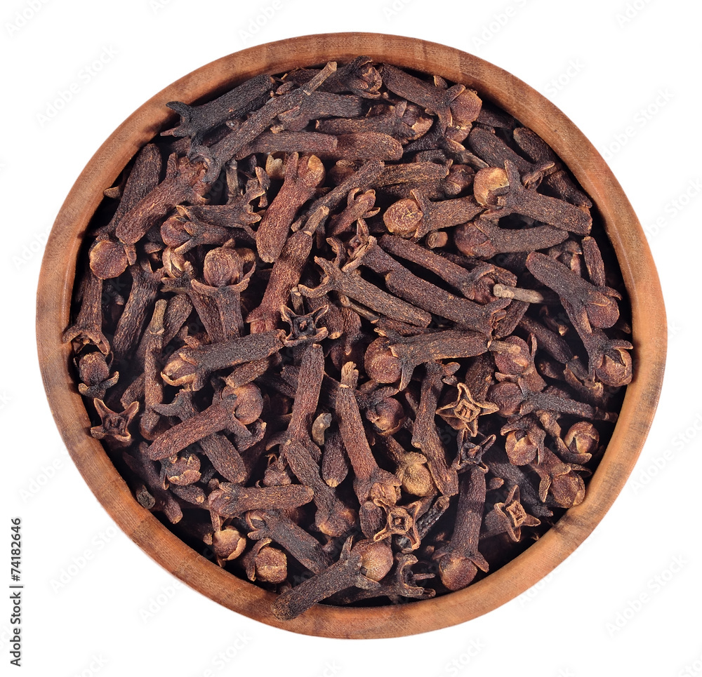 Dried clove in a wooden bowl on a white Dried clove in a wooden bowl on a white
