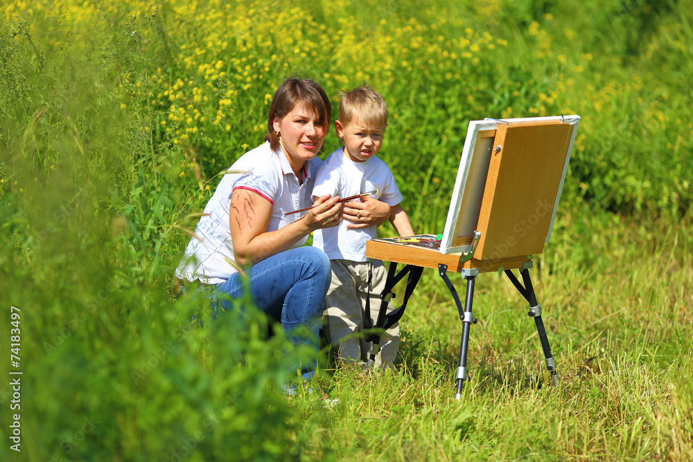 Mom and baby paint on an easel in the field Mom and baby paint on an easel in the field