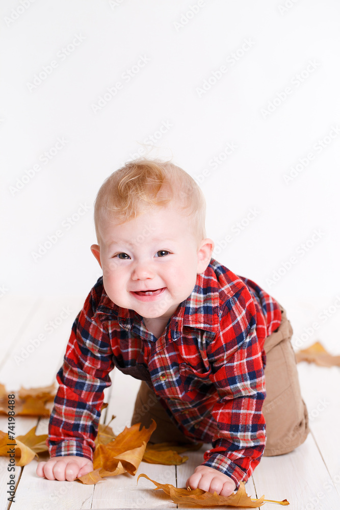 Little boy playing on the floor with maple leaves. Little boy playing on the floor with maple leaves.