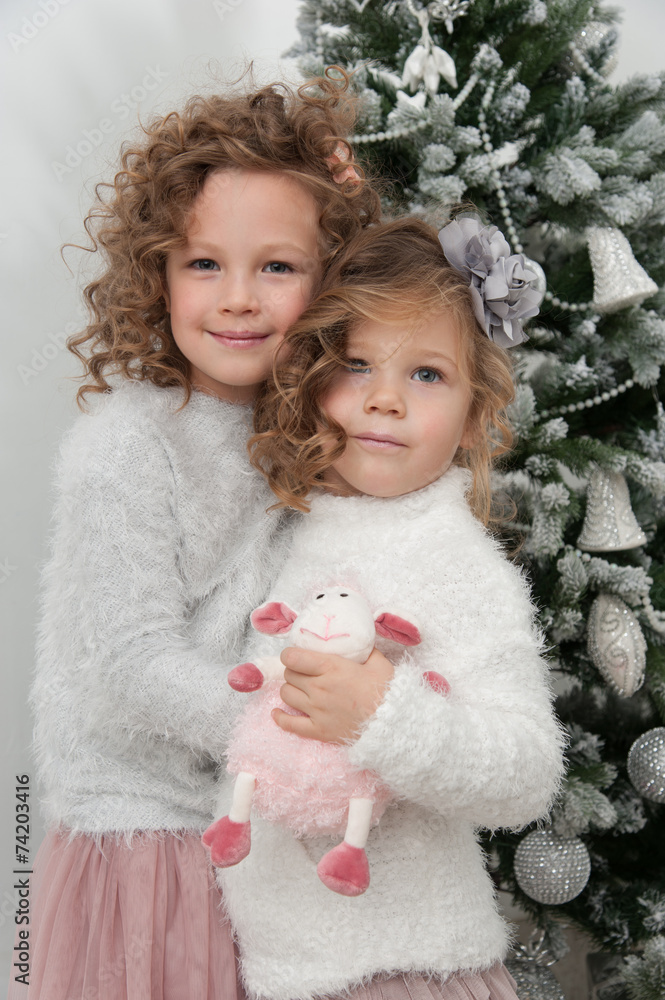 Cute child girls with sheep toy near Christmas tree