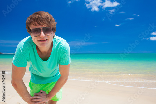 young man in sunglasses smiling at beach