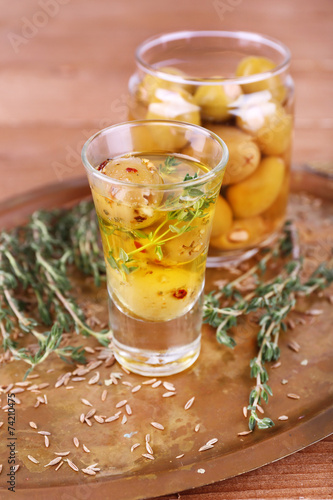 Green olives in oil with spices and rosemary in glass jars