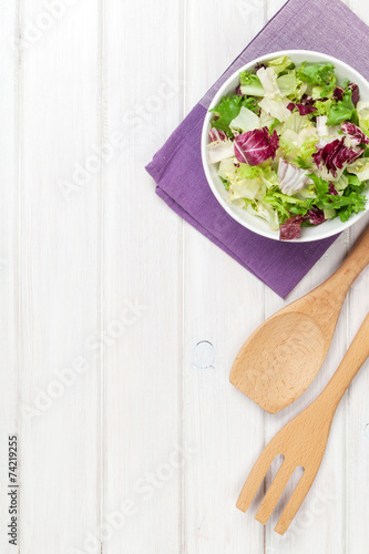 Fresh healthy salad and utensils over white wooden table