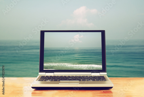 laptop with blank screen over wooden table outdoors