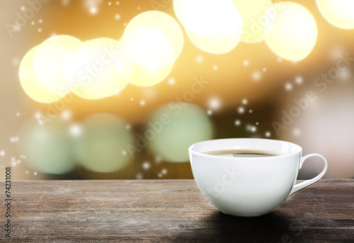 Cup of hot drink on bright background