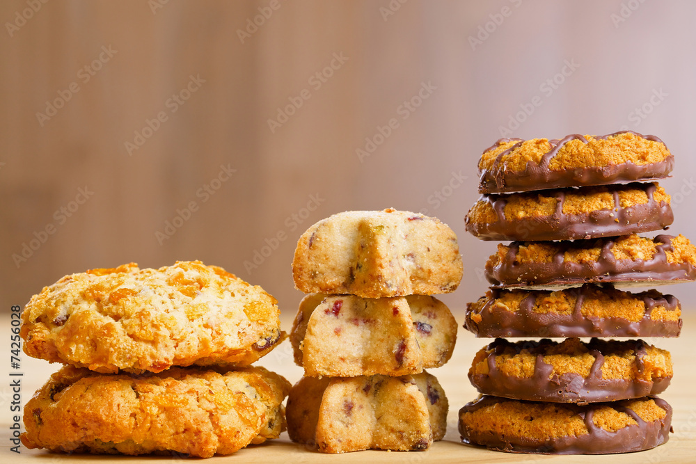 Different cookies in piles on wooden table Different cookies in piles on wooden table