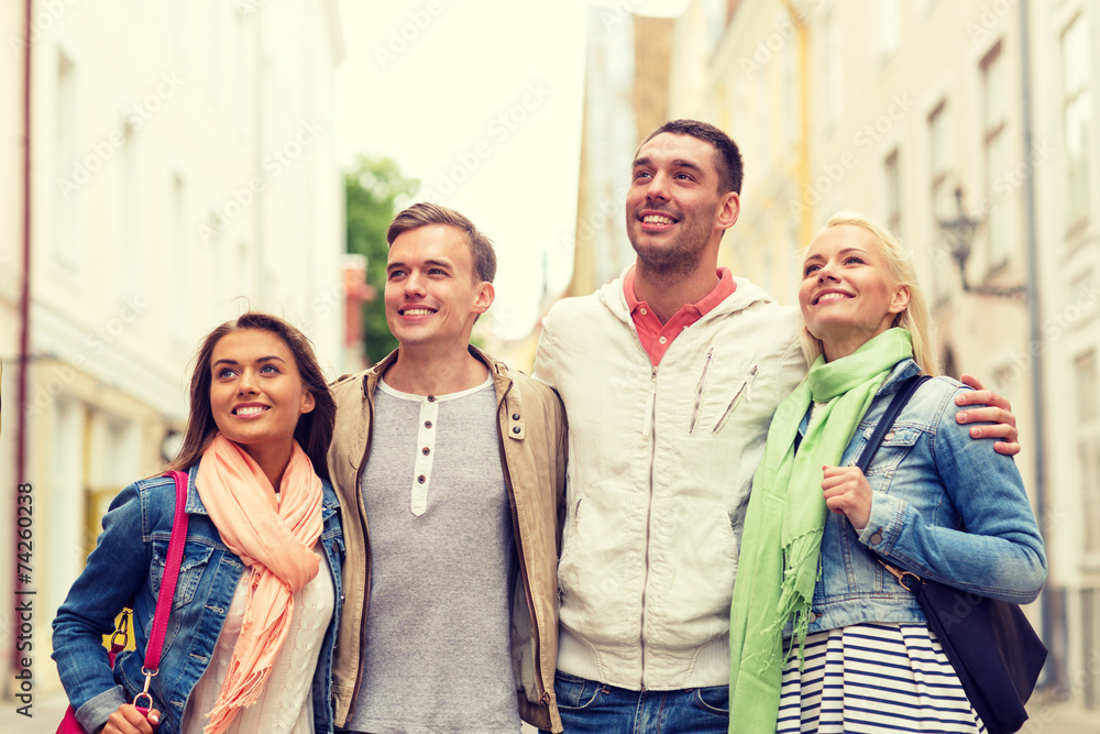 group of smiling friends walking in the city