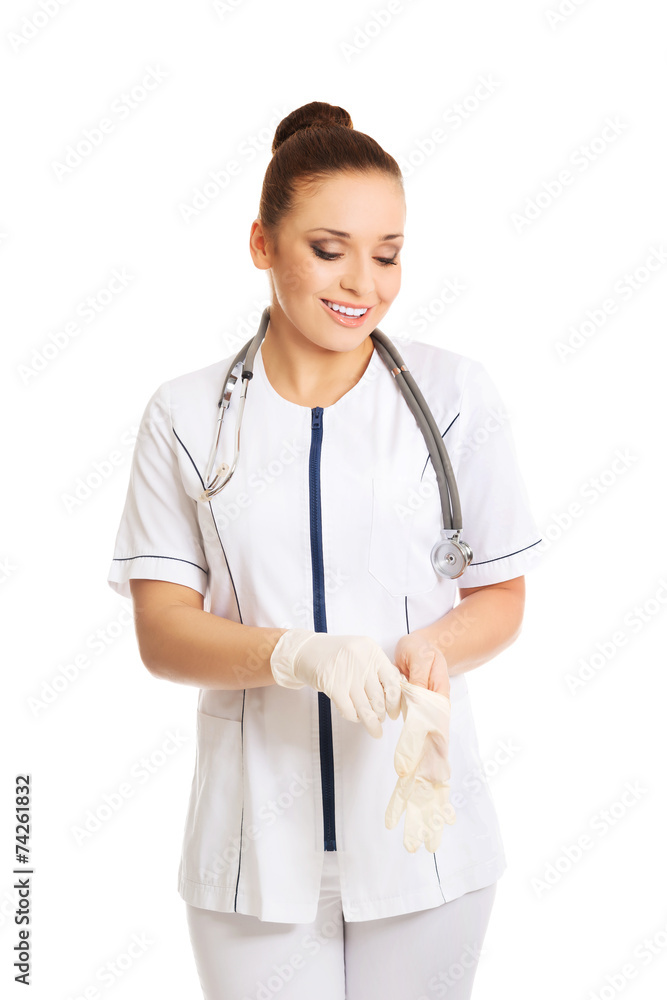 Happy female doctor putting on protective gloves Happy female doctor putting on protective gloves