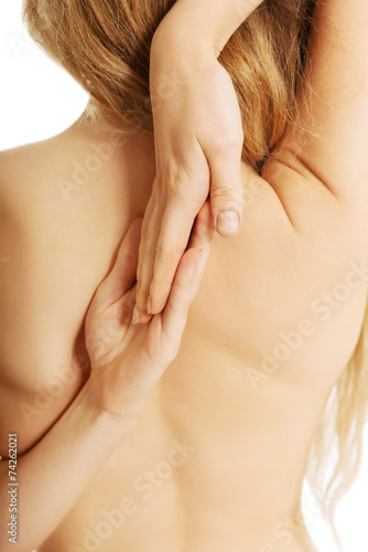 Back view of naked woman stretching arms on back