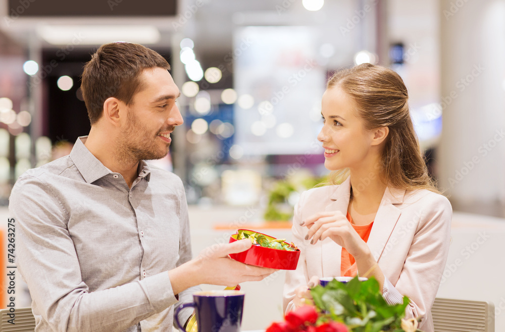happy couple with present and flowers in mall happy couple with present and flowers in mall