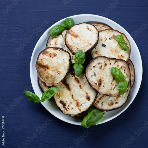 Above view of grilled aubergine slices with fresh green basil