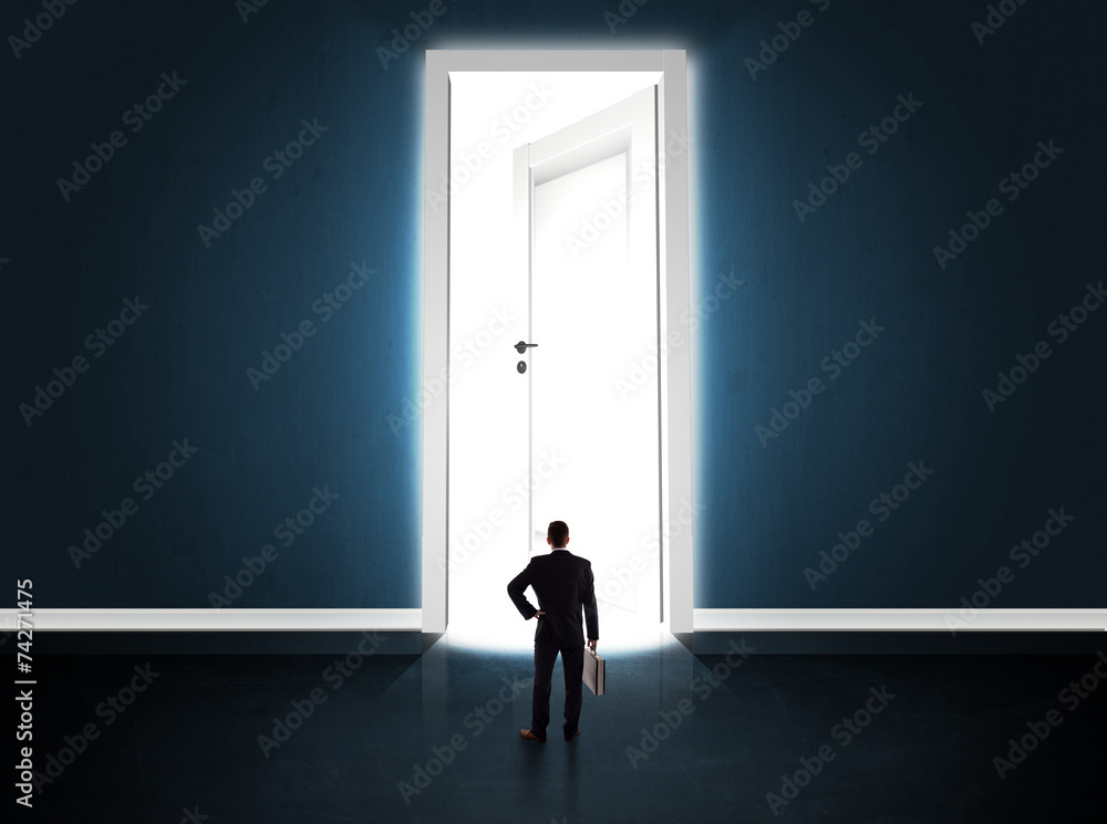 Business man looking at big bright opened door Business man looking at big bright opened door