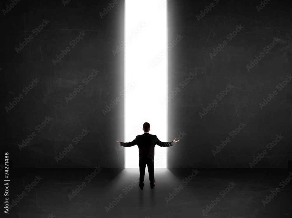 Business person looking at wall with light tunnel opening