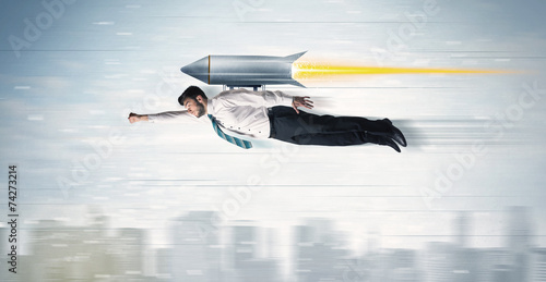 Superhero business man flying with jet pack rocket above the cit photo