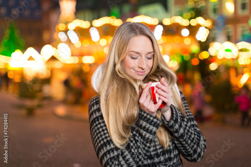 Junge Frau trinkt Glühwein auf dem Weihanchtsmarkt photo