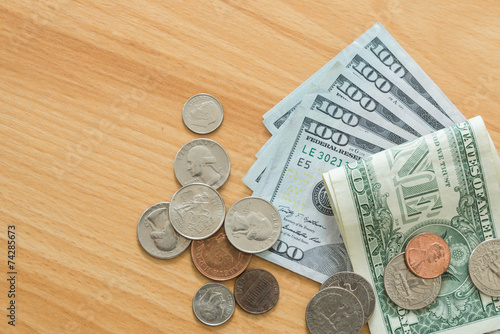 dollar bills and coins on wooden table