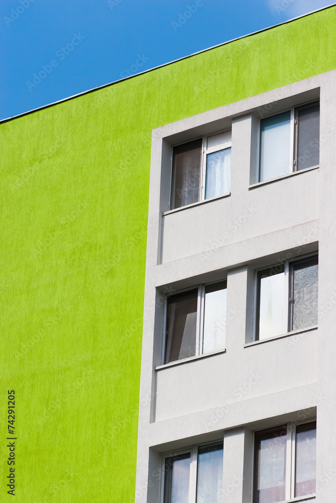 Abstract scene of a green apartment building in angle against bl
