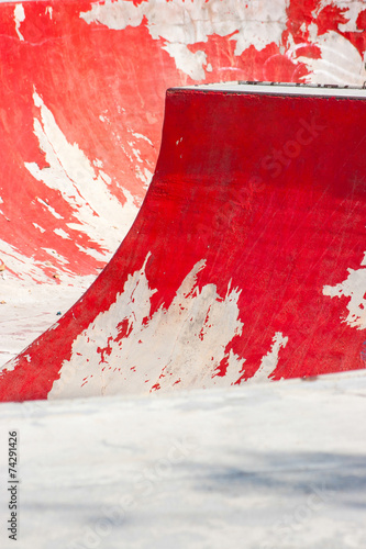 Old red skating ramp with half pipe rail.