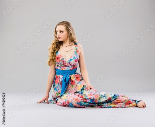 Beautiful young woman sitting in a trendy long dress