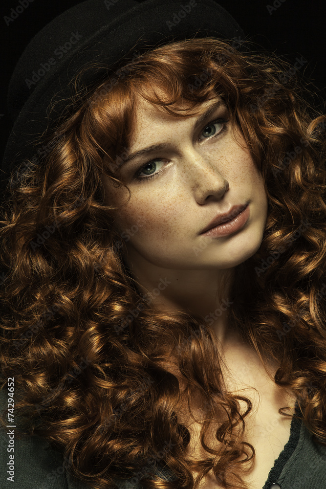 Beautiful red-haired girl with curls, black hat