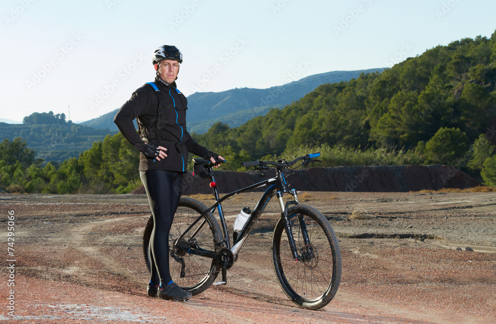 Fototapeta premium Cyclist standing with mountain bike in nature